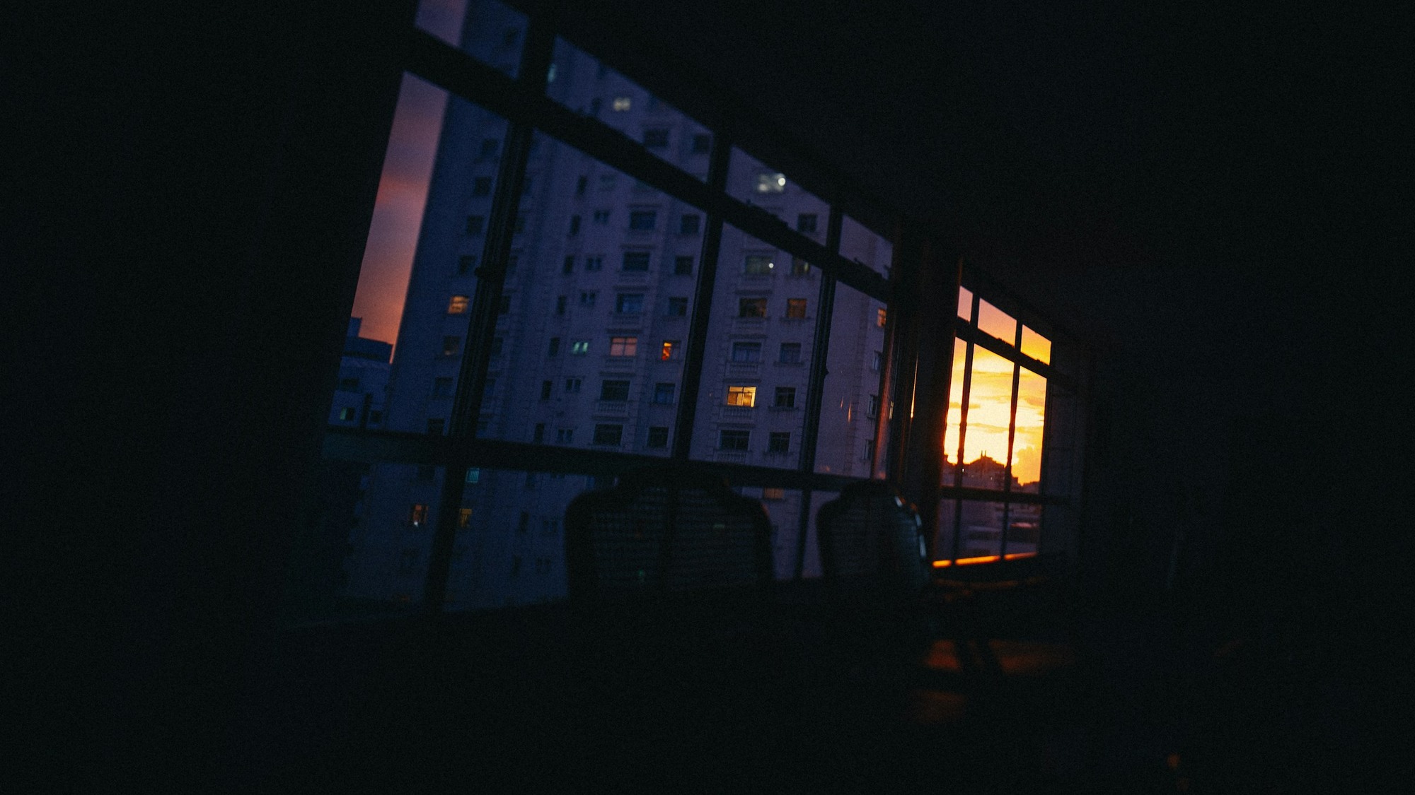 Apartment buildings seen through dark windows at sunset.